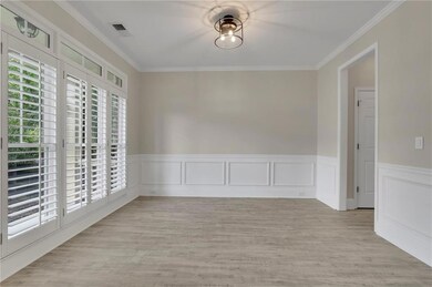 Empty room with ornamental molding, light wood-style floors, wainscoting, and a decorative wall