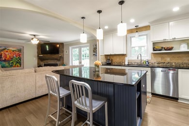 Kitchen with stainless steel dishwasher, decorative backsplash, a breakfast bar, a ceiling fan, and white cabinetry