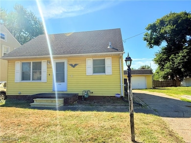 Bungalow-style home with a front lawn, roof with shingles, a garage, and an outbuilding