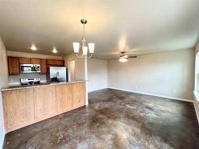 Kitchen with appliances with stainless steel finishes, finished concrete floors, a ceiling fan, a chandelier, and pendant lighting