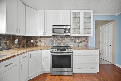 Kitchen featuring a textured ceiling, light hardwo