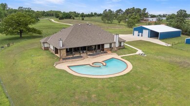 View of pool featuring an outdoor structure, fence, a pole building, a lawn, and a saltwater pool