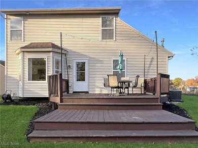 Back of house with a wooden deck, outdoor dining area, and a lawn