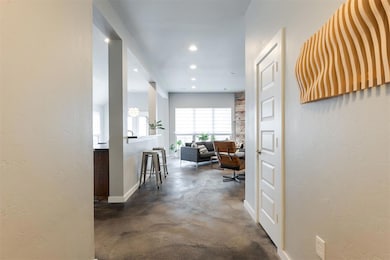 Hallway featuring concrete flooring, a textured wall, and recessed lighting