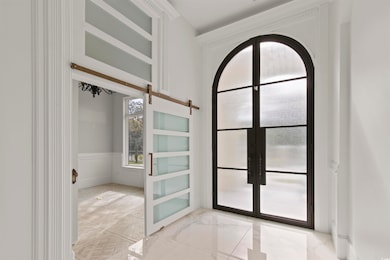 Doorway to outside with french doors, light marble finish flooring, wainscoting, and a barn door