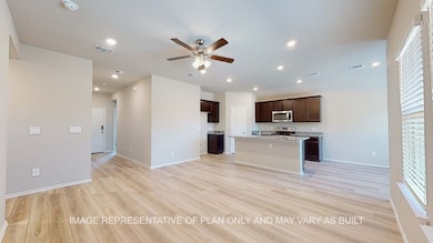 Kitchen with light wood-style flooring, a ceiling fan, dark brown cabinets, open floor plan, and a center island with sink
