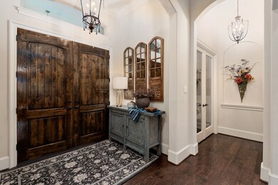 Gorgeous double door entry with decorative hanging light fixture, double crown molding, wood floors, and arched entry into the family room!
