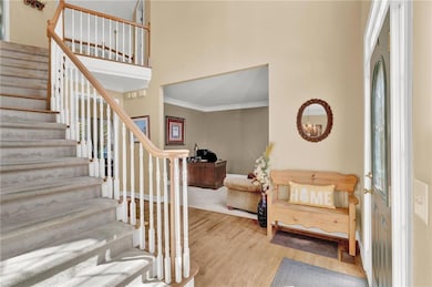 Entryway with crown molding, wood finished floors,
