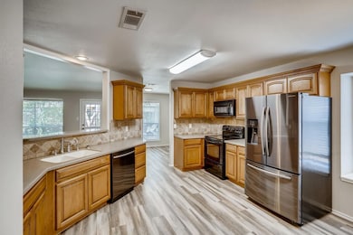 Kitchen featuring black appliances, tasteful backsplash, light wood-style floors, and brown cabinets