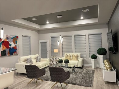 Large family/living room features a color accent tray ceiling, recessed lights, tasteful designer hanging lights.