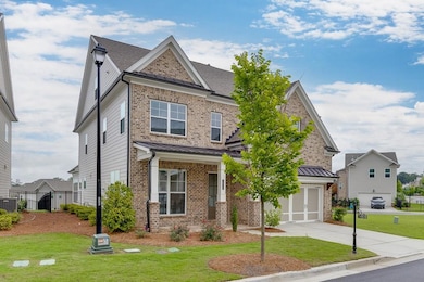 View of front facade with a garage, brick siding, concrete driveway, and a standing seam roof