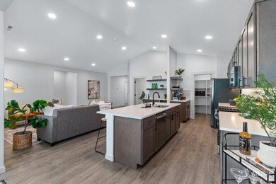 Kitchen featuring a breakfast bar area, light wood-type flooring, a kitchen island with sink, light stone counters, and recessed lighting