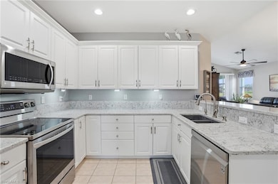 Kitchen featuring stainless steel appliances, light stone counters, white cabinets, and recessed lighting