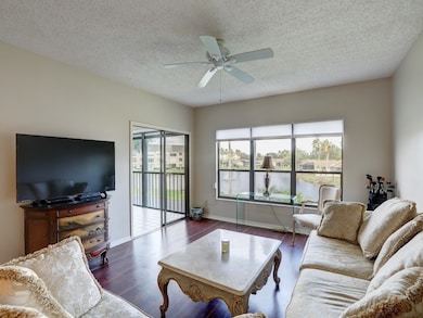 Living area featuring wood finished floors, a textured ceiling, a water view, and a ceiling fan