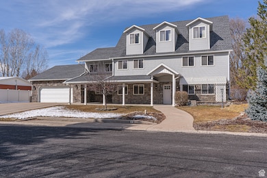 View of front of house featuring covered porch, fence, concrete driveway, stone siding, and roof with shingles