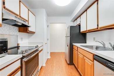Kitchen featuring sink, white cabinets, light hard
