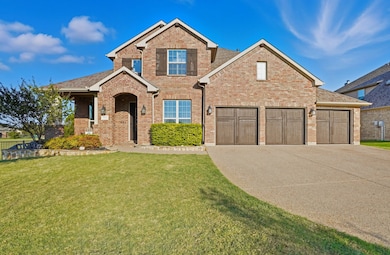 Traditional-style house with a front yard, concrete driveway, brick siding, and roof with shingles