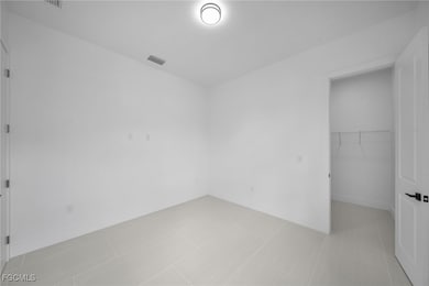Unfurnished bedroom featuring a walk in closet and light tile patterned flooring