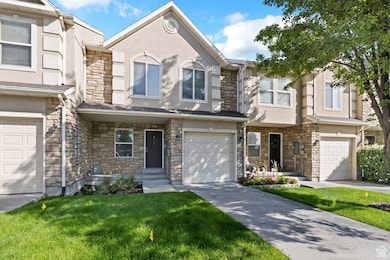 Traditional-style home with stone siding, stucco siding, an attached garage, driveway, and a front yard