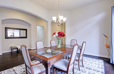 Another view of bright and airy formal dining room enriched by arched walkway and beautiful wood floors.