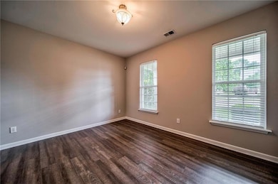 Unfurnished room with dark wood-style flooring and plenty of natural light