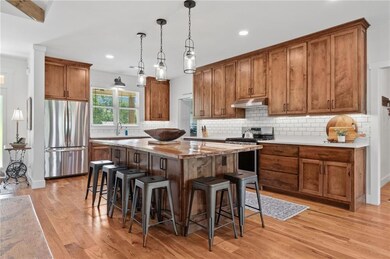 Kitchen with stainless steel appliances, a kitchen island, a breakfast bar, brown cabinets, and recessed lighting