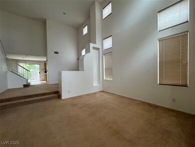 Unfurnished living room with a towering ceiling, light carpet, and stairway
