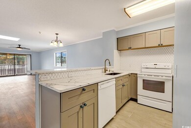Kitchen featuring white appliances, a peninsula, ornamental molding, open floor plan, and a chandelier