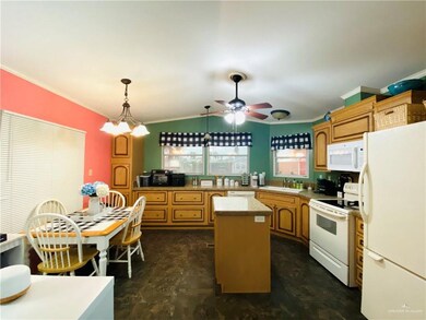 Kitchen with ceiling fan with notable chandelier, sink, white appliances, decorative light fixtures, and a kitchen island
