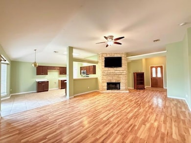 Unfurnished living room featuring a fireplace, ceiling fan, light wood-style floors, and lofted ceiling