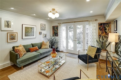 Living area featuring french doors, light wood-style flooring, crown molding, recessed lighting, and a chandelier