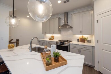 Kitchen featuring wall chimney exhaust hood, gas stove, a sink, gray cabinets, and light stone counters