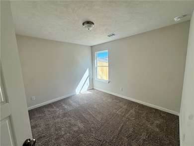Carpeted spare room featuring a textured ceiling and baseboards