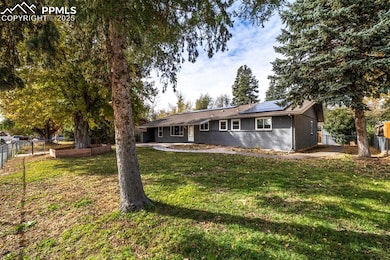 View of front of house featuring brick siding, roof mounted solar panels, a patio, and a gate