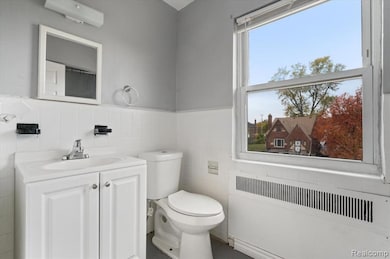 Bathroom featuring radiator heating unit, vanity, tile walls, and wainscoting