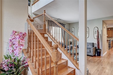 Stairs with wood finished floors and a textured wa