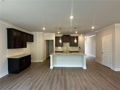 Kitchen featuring a sink, ornamental molding, baseboards, tasteful backsplash, and a center island with sink