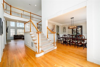Staircase with wood finished floors, ornamental molding, a chandelier, and a towering ceiling