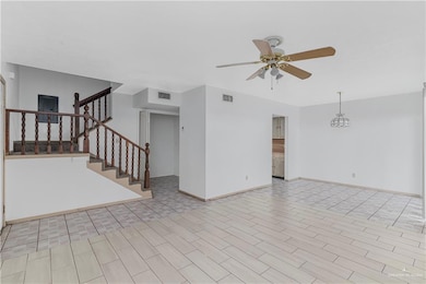 Unfurnished living room featuring a ceiling fan, stairway, and light wood-type flooring