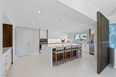 Kitchen featuring white cabinets, light stone counters, recessed lighting, stainless steel appliances, and a breakfast bar
