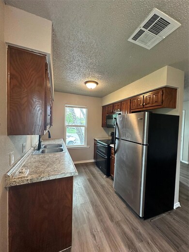 Kitchen featuring fridge, stove, a textured ceili