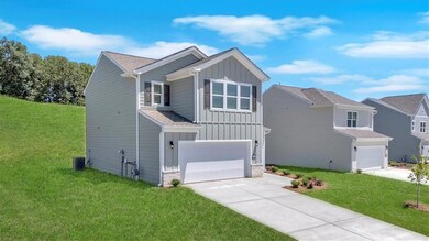 View of front facade featuring board and batten siding, an attached garage, concrete driveway, and a front yard
