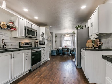 Kitchen featuring sink, white cabinetry, stainless steel appliances, dark hardwood / wood-style floors, and decorative backsplash