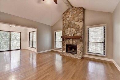 Unfurnished living room with ceiling fan, wood finished floors, and a stone fireplace
