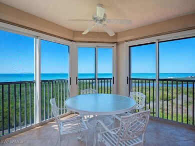 Sundrenched lanai looking west to Gulf and sunsets featuring a ceiling fan, a water view, and a beach view