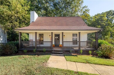 View of front of home featuring board and batten siding, roof with shingles, covered porch, and a front yard