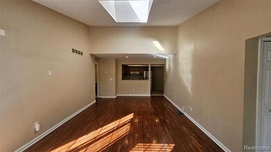 Hallway featuring a skylight, dark wood finished floors, and a towering ceiling
