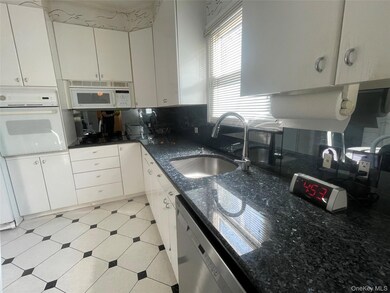 Kitchen featuring white appliances, white cabinetry, dark stone countertops, and tasteful backsplash