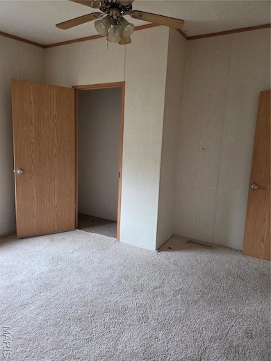Unfurnished bedroom with crown molding, a textured ceiling, carpet floors, and a ceiling fan