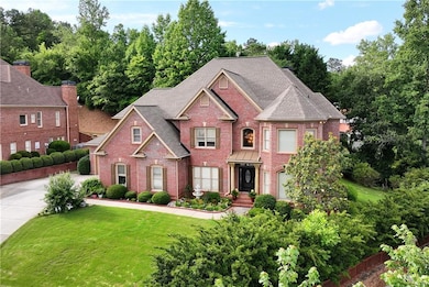 Colonial-style house with brick siding, a front lawn, and view of wooded area